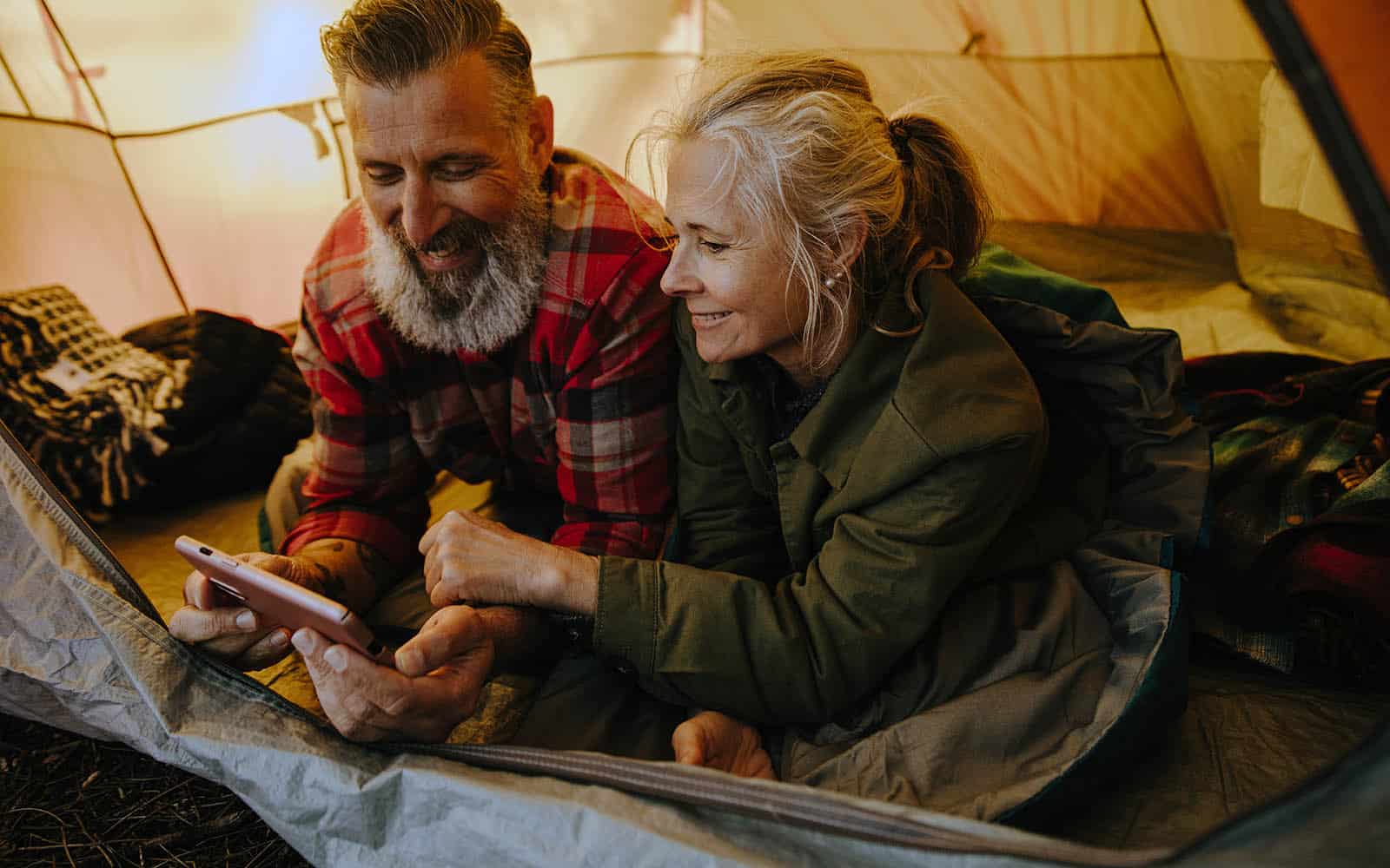 Couple Watching Videos While Camping in Tent