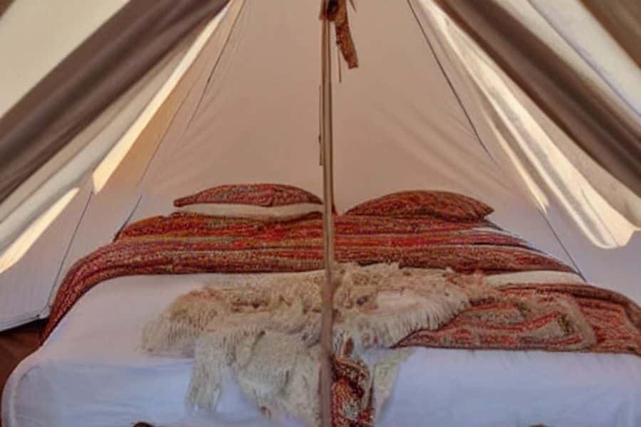 Beautiful Bed with a Comforter and Pillows Inside a Bell Tent
